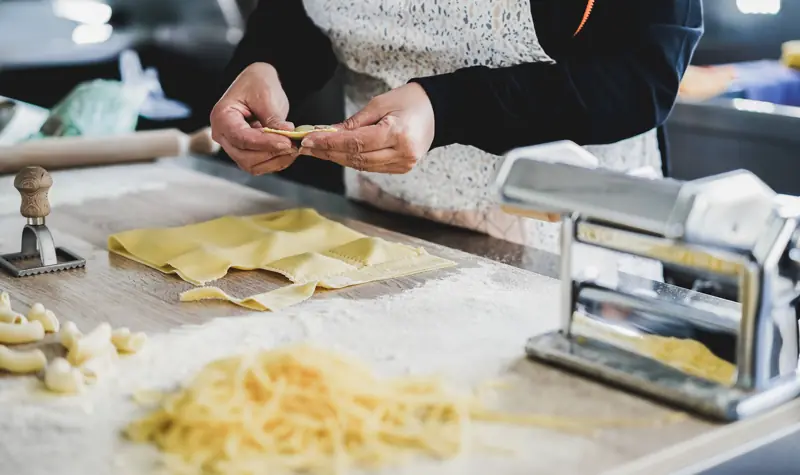 Mani che preparano ravioli in un pastificio